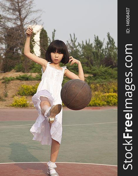 The asian girl is playing with a basketball with great fun. The asian girl is playing with a basketball with great fun