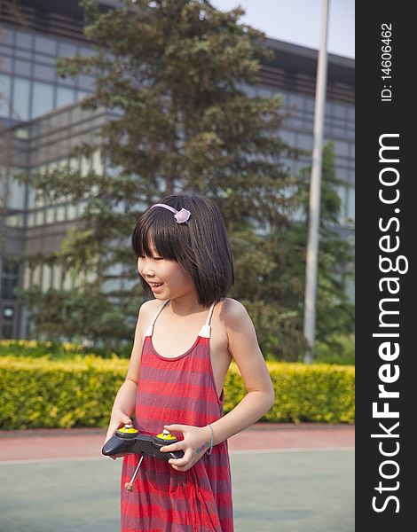 The asian girl is playing the remote controlled toy with great fun in summer. The asian girl is playing the remote controlled toy with great fun in summer