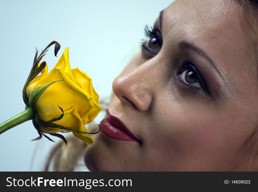 Portrait of the beautiful young woman holding single yellow rose flower.