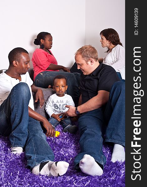 Young group of multiracial friends - two young families enjoying an afternoon meeting at home. Young group of multiracial friends - two young families enjoying an afternoon meeting at home.