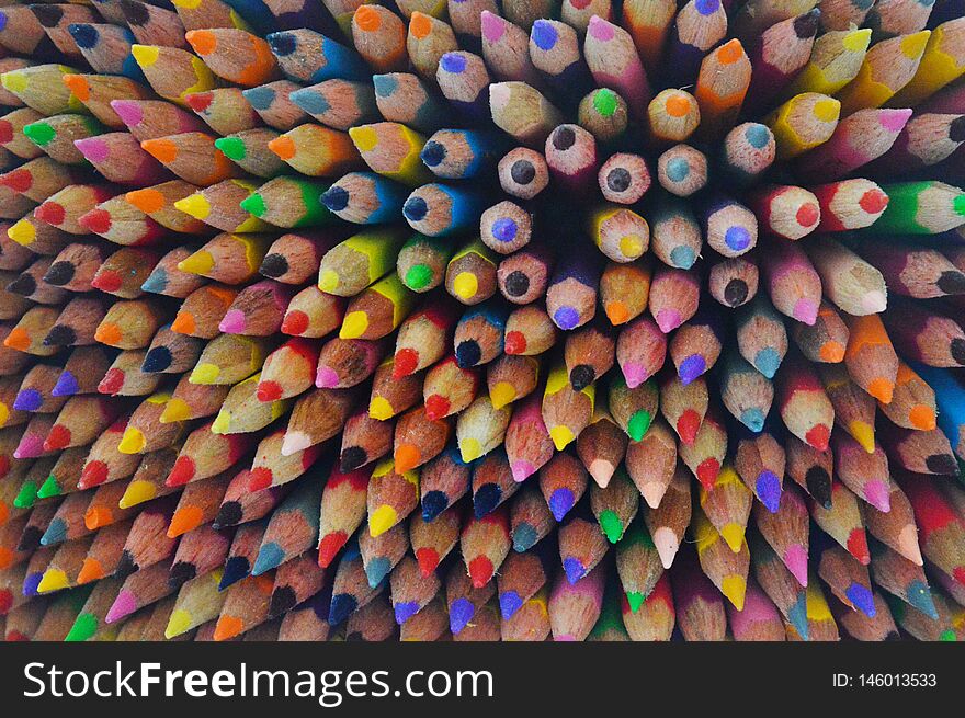 Differently colored wooden crayons arranged perpendicularly. Different shades of yellow, green, red, orange, blue, white and black. Differently colored wooden crayons arranged perpendicularly. Different shades of yellow, green, red, orange, blue, white and black.