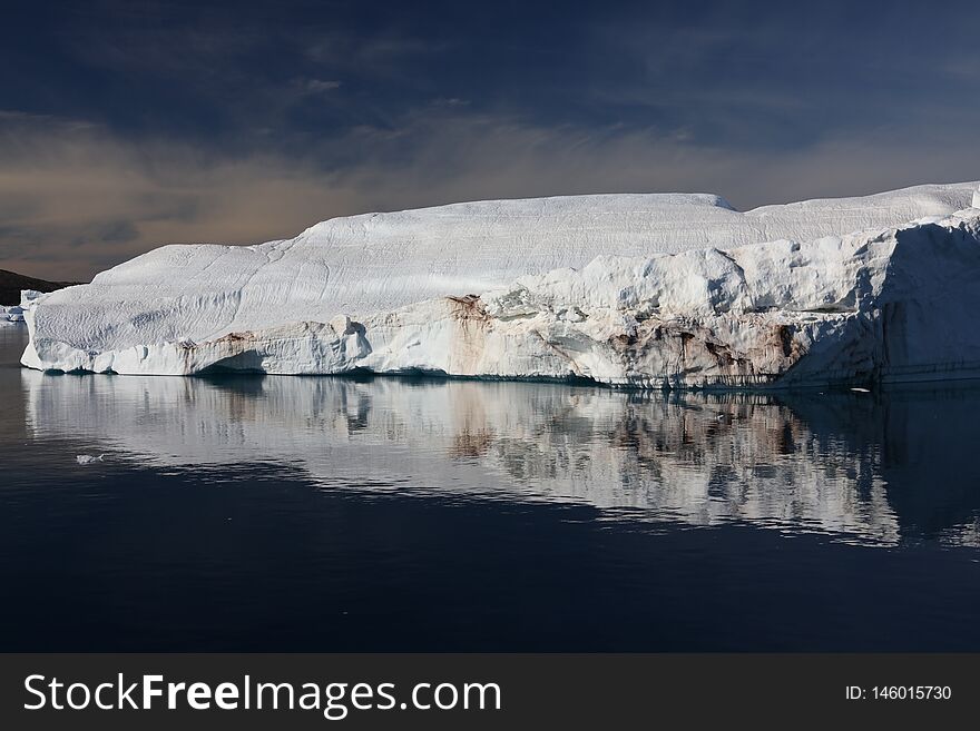A Large Iceberg And Its Reflection In Calm Fjord Waters In Northwest Greenland