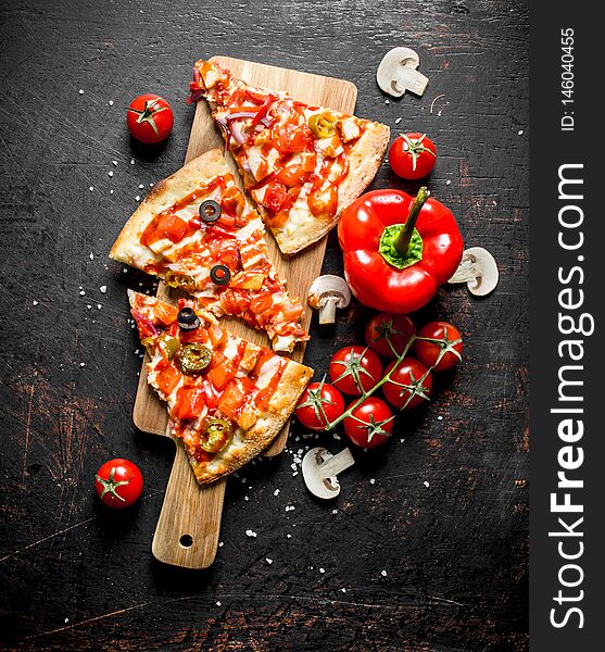 Slices of Mexican pizza with bell peppers and tomatoes. On dark rustic background