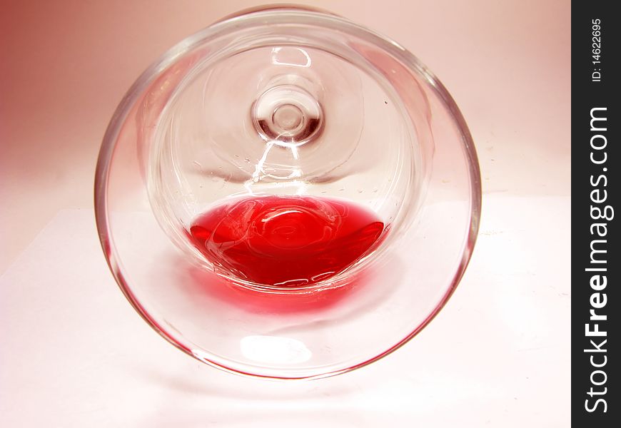 Pouring goblet of red wine on pink background