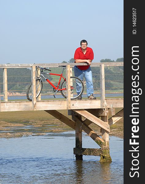 Fat man resting on the seaside over wooden bridge looking to the landscape resting. Fat man resting on the seaside over wooden bridge looking to the landscape resting