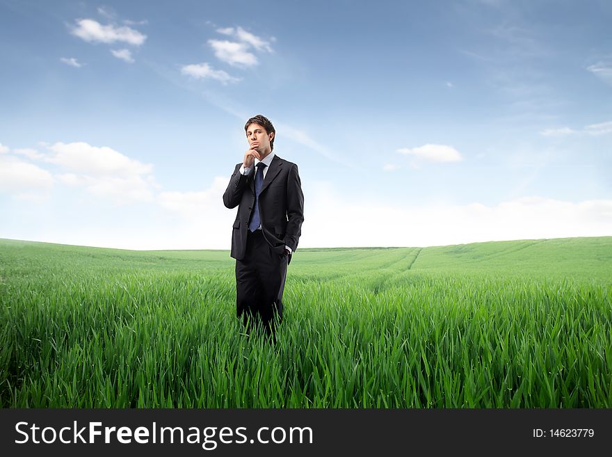 Businessman standing on a green meadow and reflecting. Businessman standing on a green meadow and reflecting