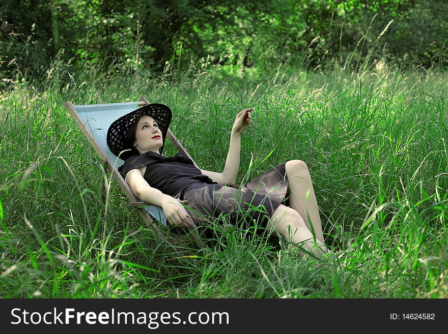 Young woman lying on a deckchair on a green meadow. Young woman lying on a deckchair on a green meadow