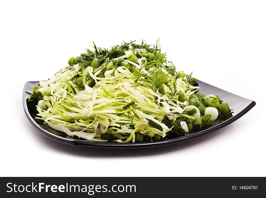 Green vegetarian salad on black plate isolated on white