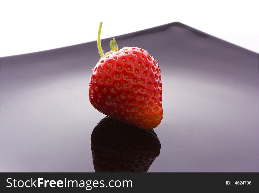 Red strawberry on black plate isolated on white