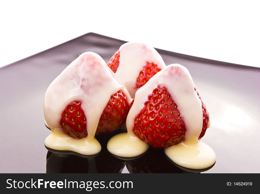 Red strawberry on black plate isolated on white