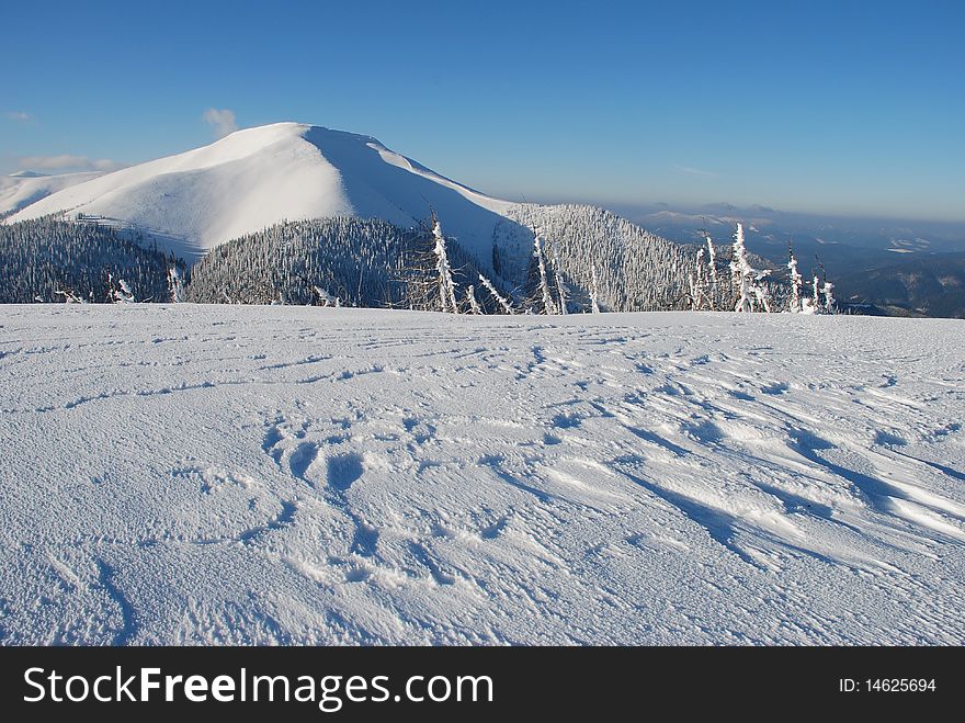 White mountain with the dark blue sky in a winter landscape with a snow hillside. White mountain with the dark blue sky in a winter landscape with a snow hillside.