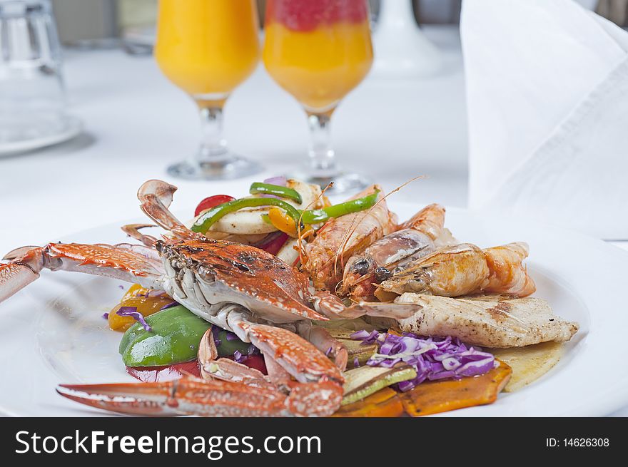 Fresh seafood meal of swimming crab and tiger shrimps with salad on a white plate with fresh fruit drinks. Fresh seafood meal of swimming crab and tiger shrimps with salad on a white plate with fresh fruit drinks