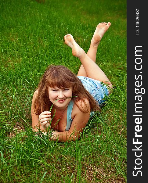 Portrait of a beautiful smiling female lying on a grass, it is summer and she is holding a blade of grass. Portrait of a beautiful smiling female lying on a grass, it is summer and she is holding a blade of grass