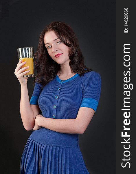 Beauty woman in blue dress with yellow orange juice on black background