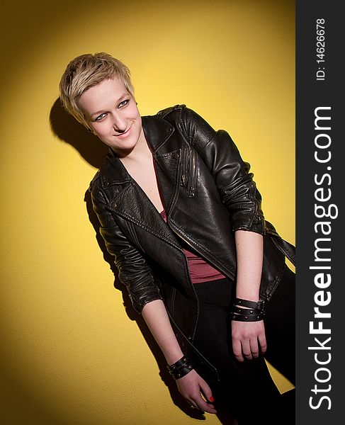 Smiling woman in leather jacket on yellow background