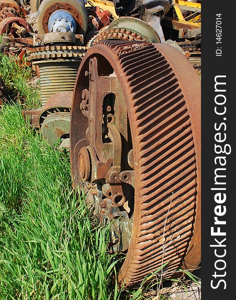 Old rusty heavy industrial machine gear cogwheel on the grass. Old rusty heavy industrial machine gear cogwheel on the grass