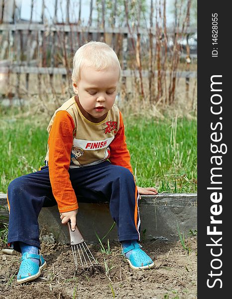 Young Boy digging in the ground in the country, young rake