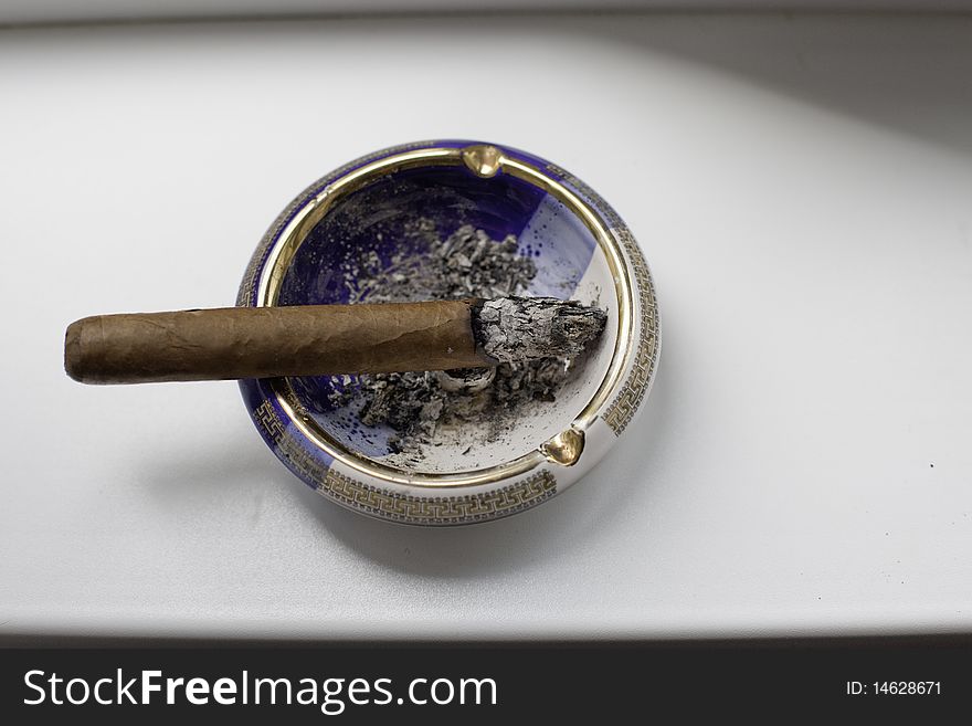 Cuban cigar on an elegant ashtray over a white background. Cuban cigar on an elegant ashtray over a white background