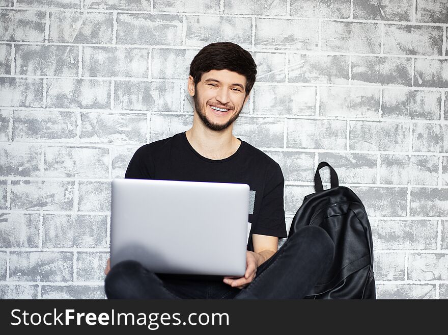 Young man smiling with laptop in his hands.