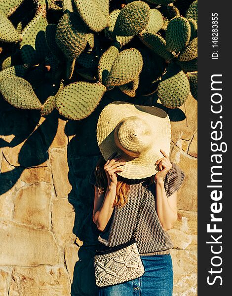 Woman near a stone fence with cacti