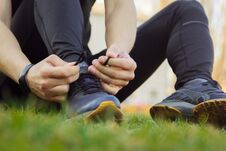 A Young Man In Black Clothes Is Tying The Laces On The Sneakers Close Up. Fitness Athlete Sitting On The Sports Field On The Grass Royalty Free Stock Image A Young Man In Black Clothes Is Tying The Laces On The Sneakers Close Up. Fitness Athlete Sitting On The Sports Field On The Grass Royalty Free Stock Image