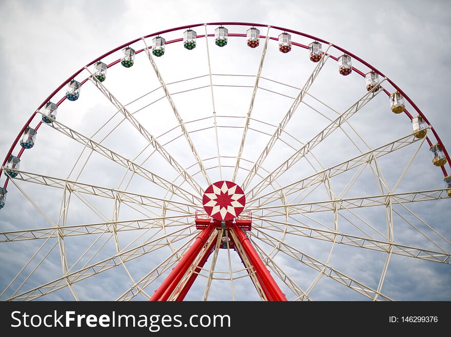 Ferris wheel in an amusement park on a background of clouds. Ferris wheel in an amusement park on a background of clouds