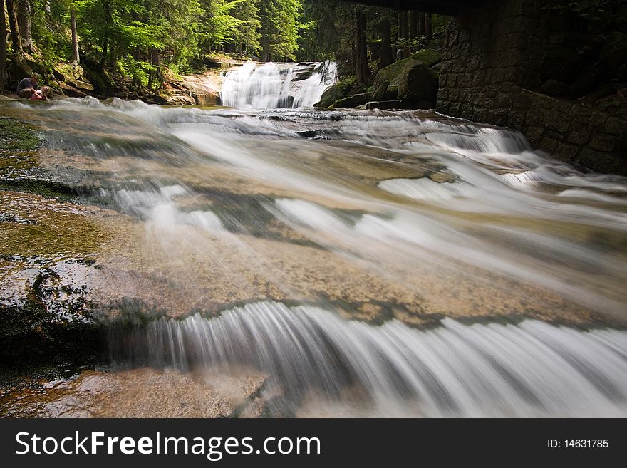 Stream below waterfall, stones and wood