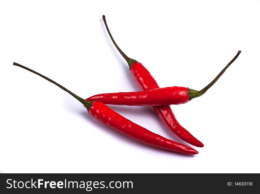 Three red chillies on a white background