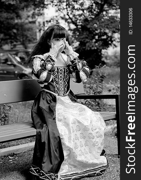 A girl in medieval dress sitting on a bench. A girl in medieval dress sitting on a bench