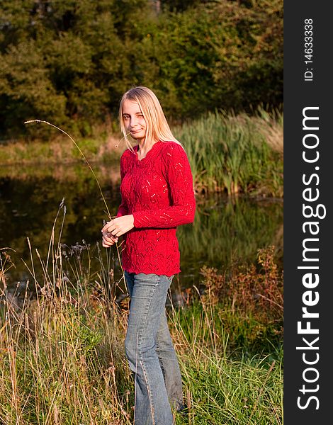 A girl in red pullover in a forest near pond