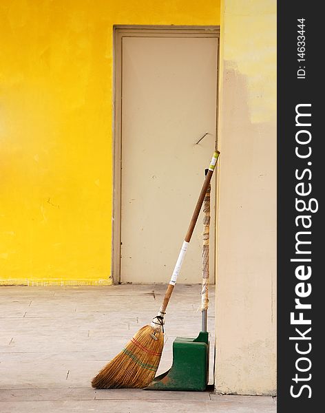 Broom and dustpan on a yellow wall
