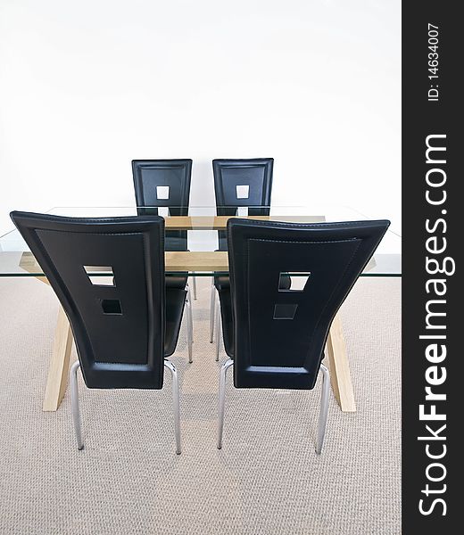 Detail of a modern dining table with leather chairs and glass top. Detail of a modern dining table with leather chairs and glass top