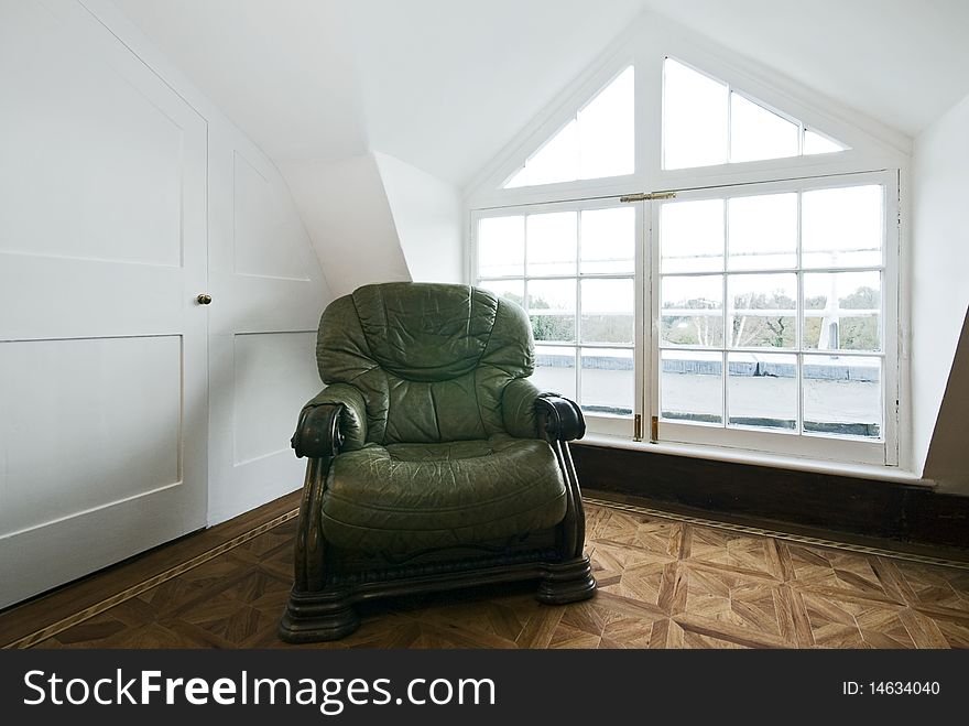 Detail shot of a living room with a bay window and green vintage leather armchair. Detail shot of a living room with a bay window and green vintage leather armchair