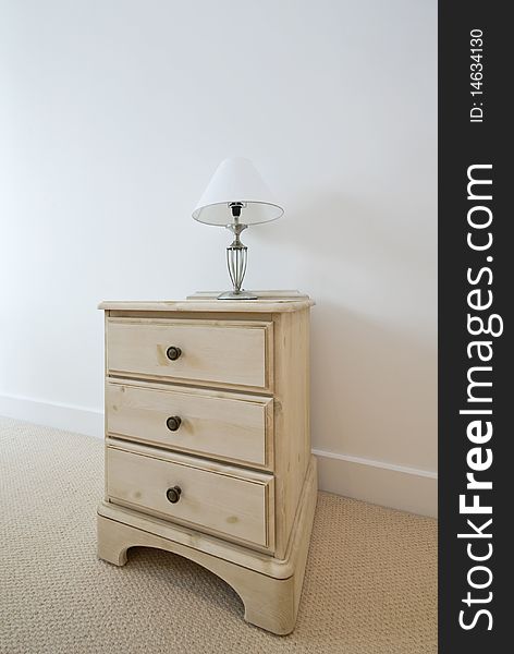 Detail of a classic wooden bedside table with a reading lamp