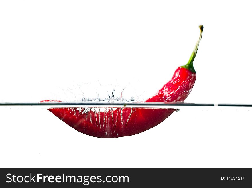 Red hot chili pepper splashing into water isolated on white. Red hot chili pepper splashing into water isolated on white