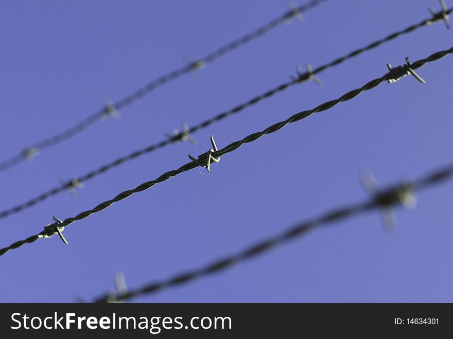 Barbwire (barbed wire) in front of the bright blue sky.