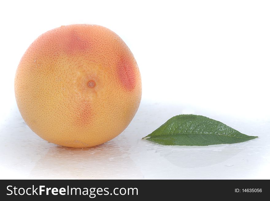 Large grapefruit isolated on white background with a green leaf