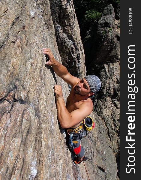 Male rock-climber  on a granite wall. Male rock-climber  on a granite wall