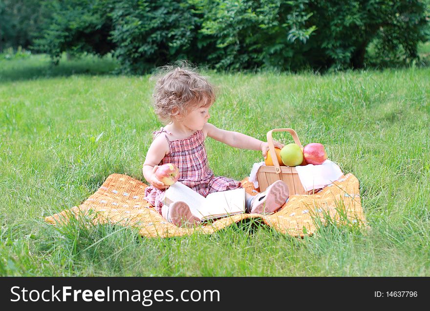 Small lovely girls with fruits and book in the park. Small lovely girls with fruits and book in the park
