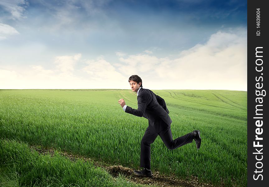 Young businessman running on a green meadow. Young businessman running on a green meadow