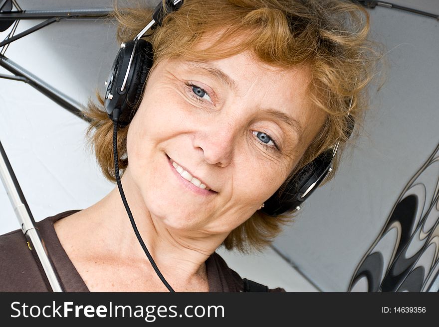 Portrait of middle-aged woman under an umbrella in your headphones