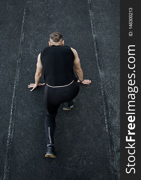 Caucasian man doing a sprint start. running on the stadium on a track. Track and field runner in sport uniform. energetic physical activities. outdoor exercise, healthy lifestyle. vertical top view