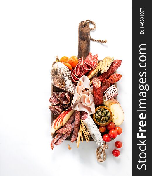 Cold meat plate, charcuterie on white background with copy space. Traditional Spanish tapas selection - chorizo, salchichon, jamon serrano, lomo, salami. Top view
