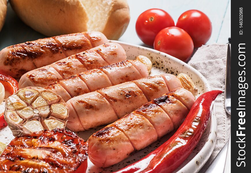 Close up view of chicken homemade sausages with buns bread. Grilled sausages and grilled vegetables in craft trendy plate. Home hotdogs. Close up view of chicken homemade sausages with buns bread. Grilled sausages and grilled vegetables in craft trendy plate. Home hotdogs.