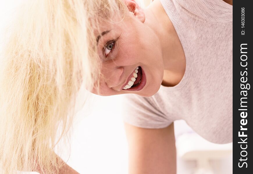 Happy woman playing with blonde hair. Positive clean female after taking a shower feeling clean and relaxed. Unusual crazy bottom angle