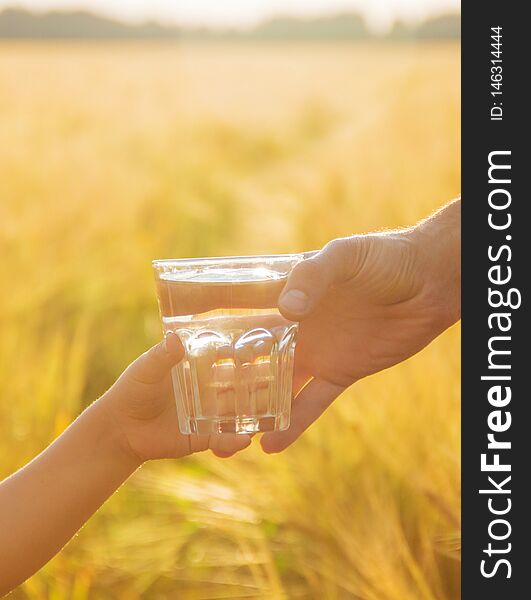 The father gives the child a glass of water. Selective focus. nature