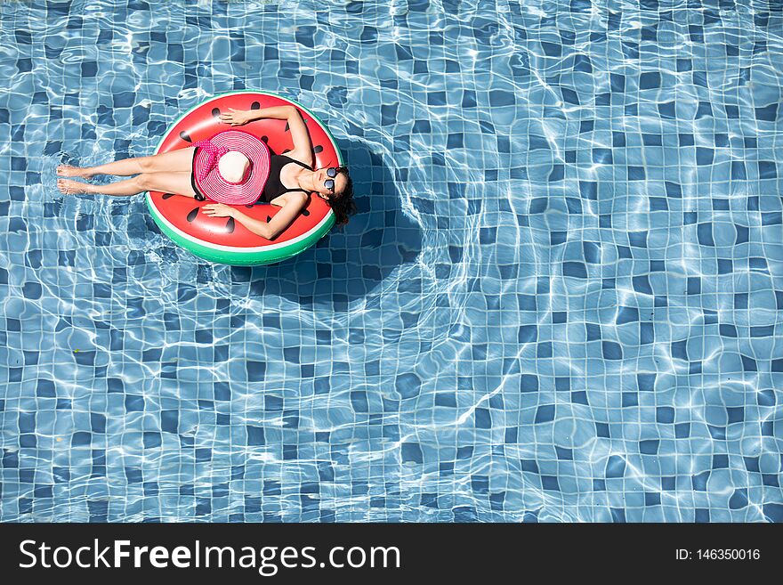 Top view shot woman wear sunglasses laying on balloon in blue water swimming pool with copy space, concept for luxury and happy lifestyle. Top view shot woman wear sunglasses laying on balloon in blue water swimming pool with copy space, concept for luxury and happy lifestyle