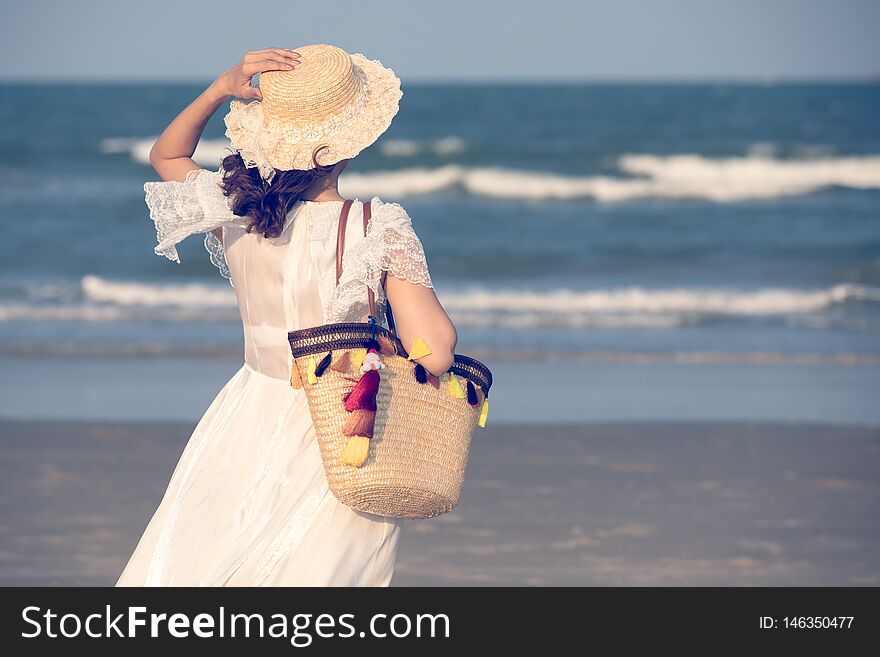 Woman carry big handcraft bag wearing beautiful hat standing and looking to sea with wave and background. Woman carry big handcraft bag wearing beautiful hat standing and looking to sea with wave and background
