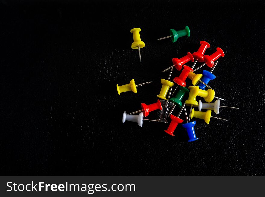 Top view of colorful thumbtacks on a black background. Top view of colorful thumbtacks on a black background
