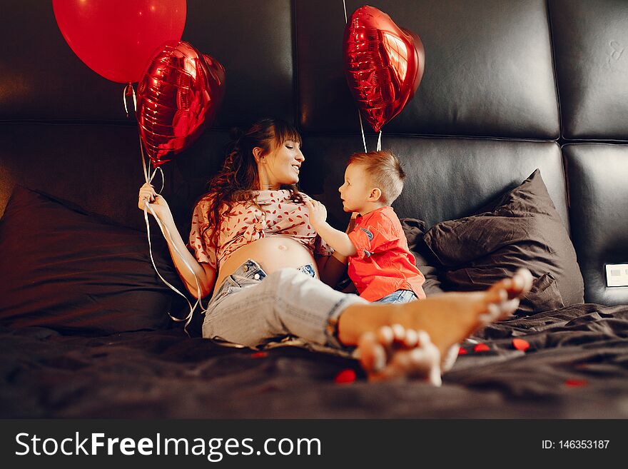 Pregnant women at home. Mother with son in a bed. Family in a room with decorstions for Valentine`s day. Pregnant women at home. Mother with son in a bed. Family in a room with decorstions for Valentine`s day